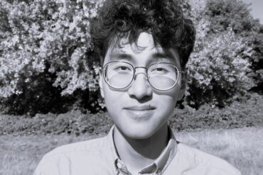 Foto dell'autore in bianco nero. Sullo sfondo, un albero in un parco.