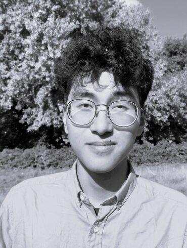 Foto dell'autore in bianco nero. Sullo sfondo, un albero in un parco.