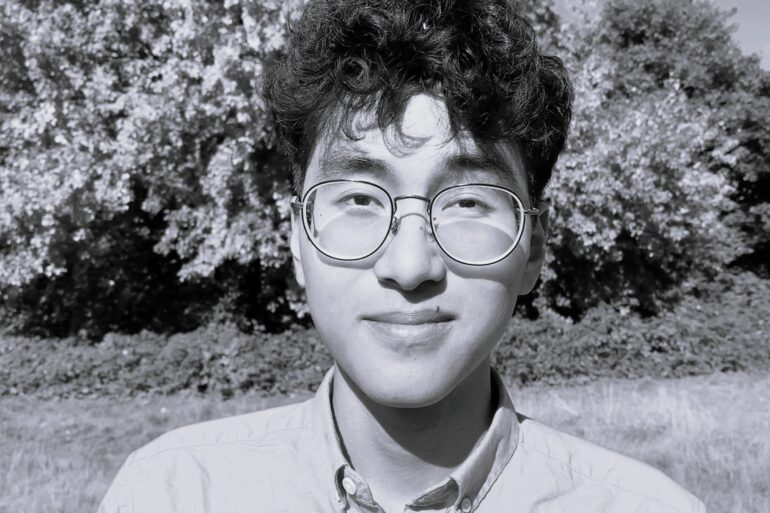 Foto dell'autore in bianco nero. Sullo sfondo, un albero in un parco.