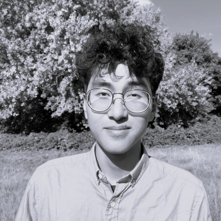 Foto dell'autore in bianco nero. Sullo sfondo, un albero in un parco.